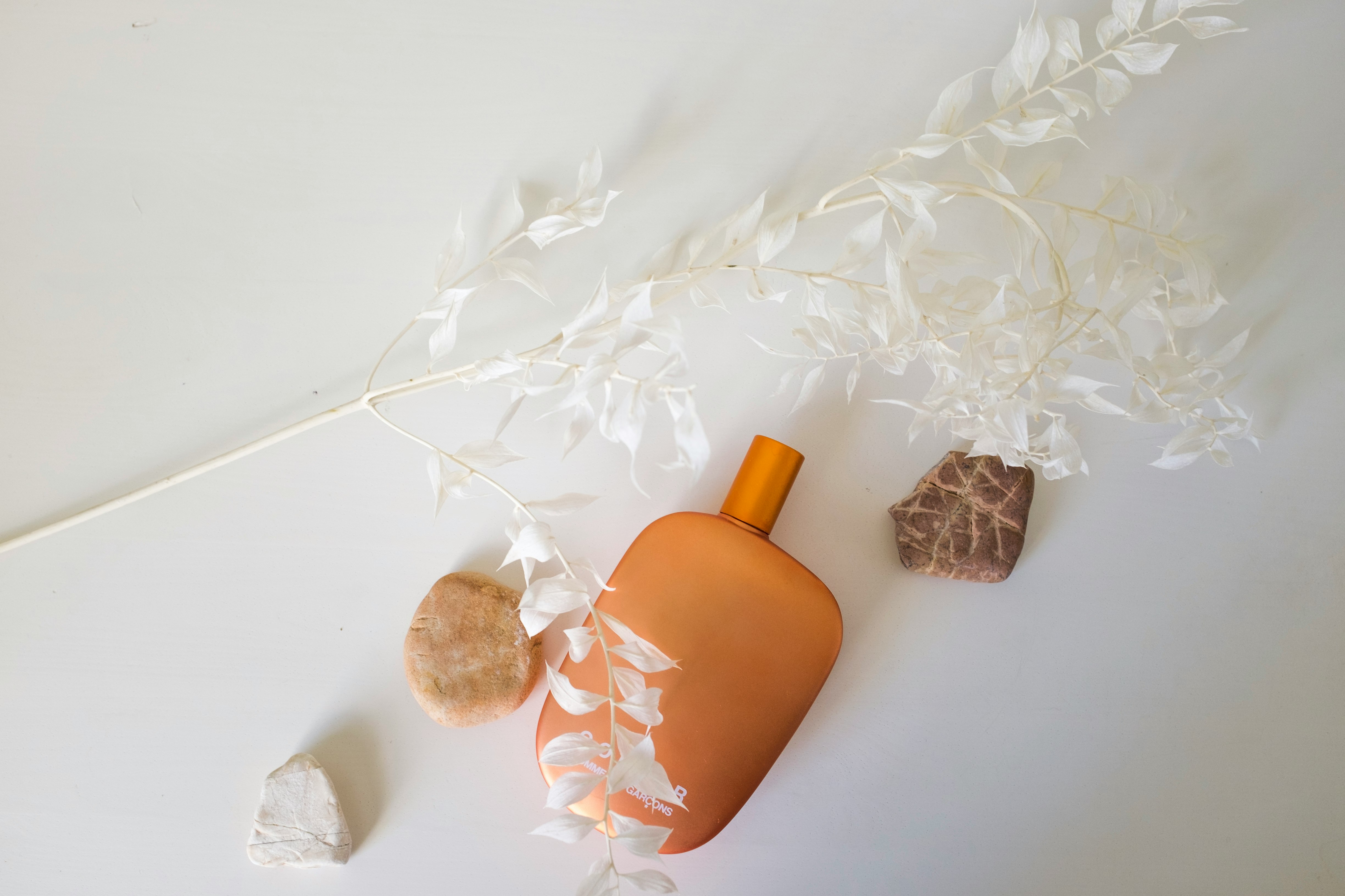 orange bottle beside white and brown floral textile